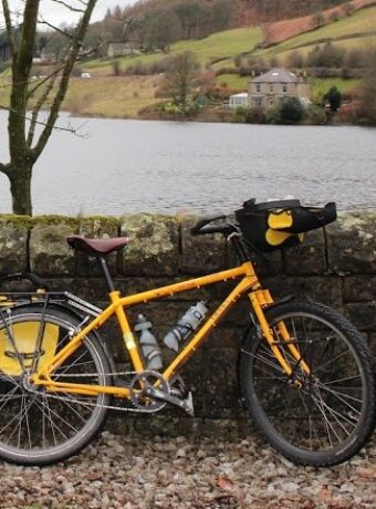 Photograph of a yellow bicycle leaning against a dry stone wall