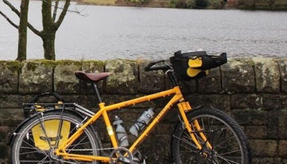 Photograph of a yellow bicycle leaning against a dry stone wall